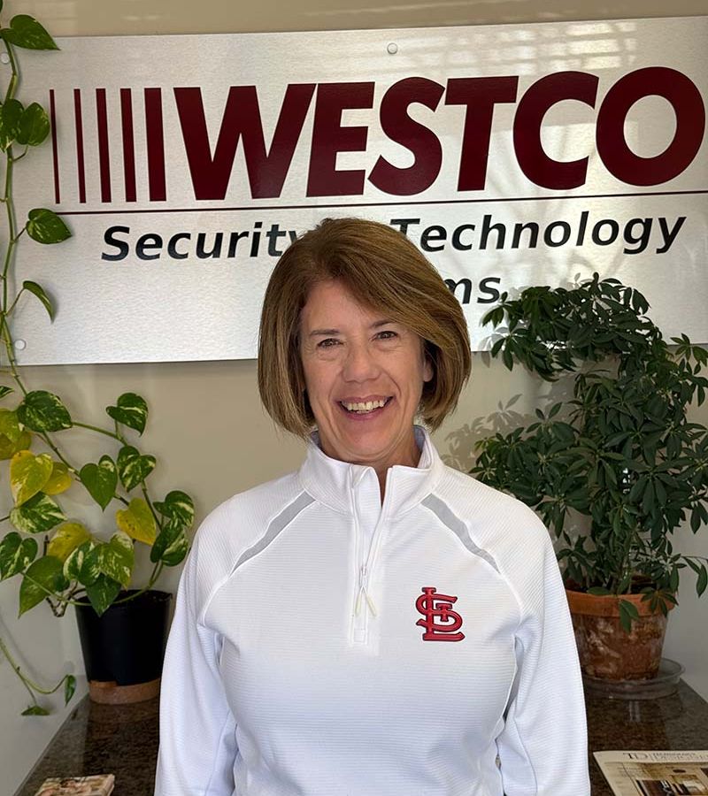 A professional portrait of Kelly, a smiling individual in business casual attire, set against a neutral background.