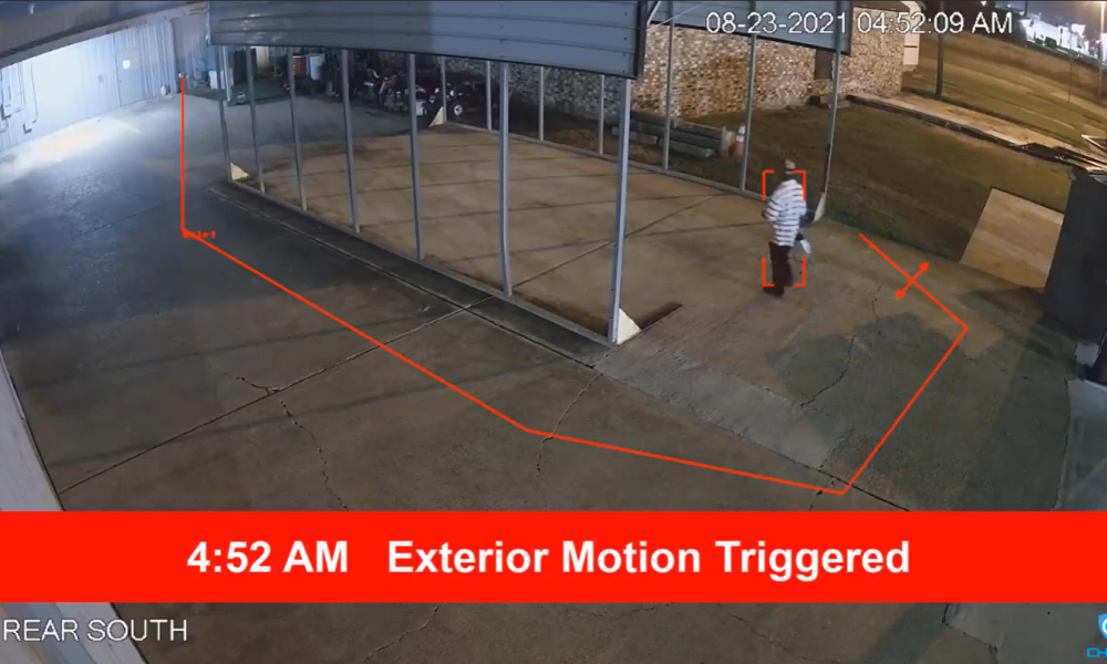 Security camera view of a person detected at 4:52 AM with a red motion alert banner and digital perimeter tracking.
