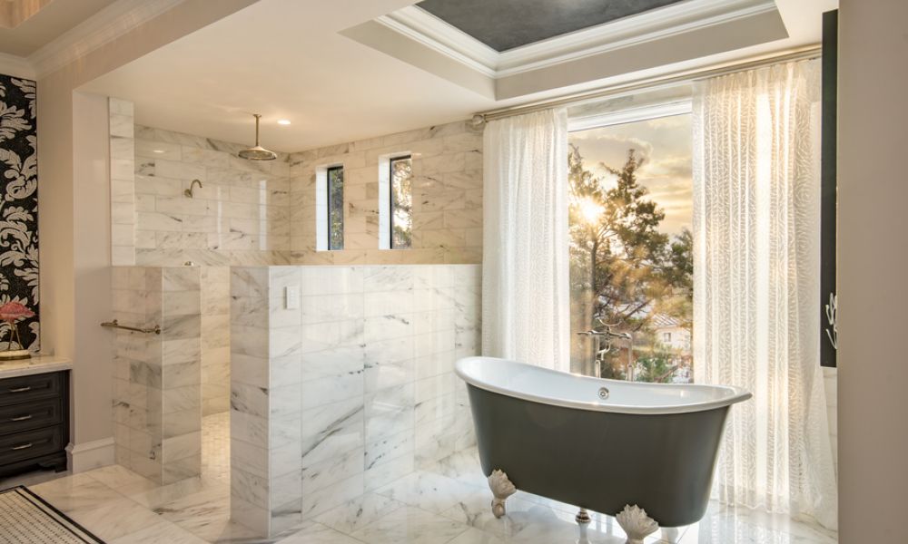 A bathroom illuminated by Ketra Lighting with a clawfoot bathtub and sunlight streaming through the window.