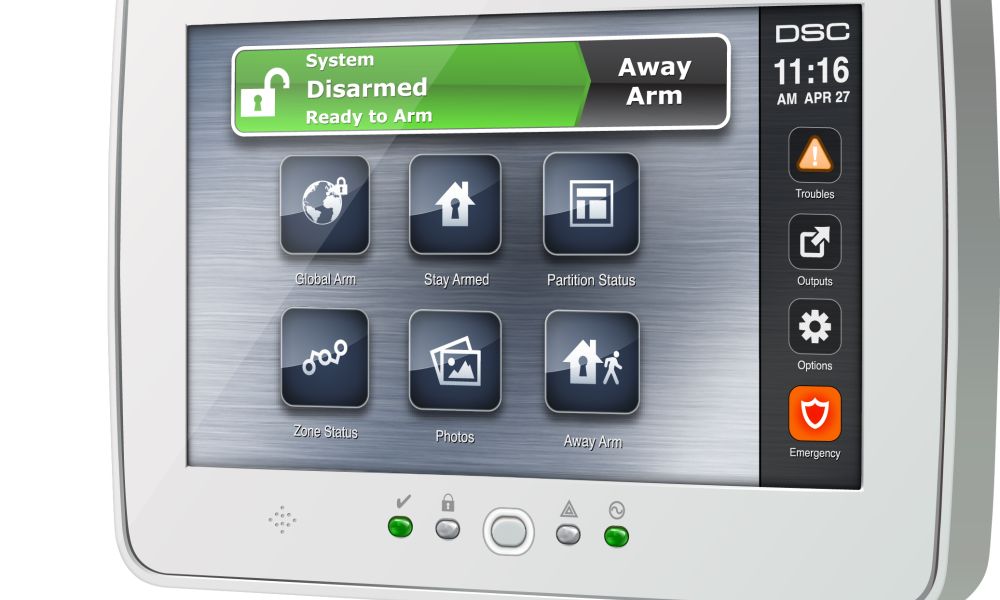 Close-up of a touchscreen home security control panel showing the system status as “Disarmed – Ready to Arm,” with large icons for arming modes, zone status, photos, and an emergency button along the right side.